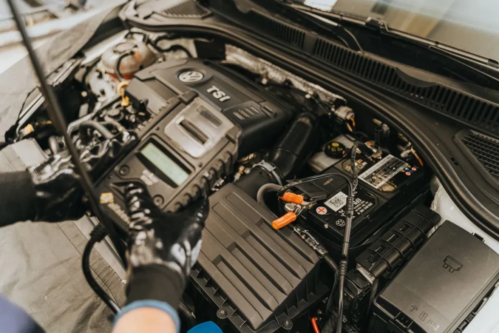Técnico realizando prueba de diagnóstico con escáner a baterías de auto en Santiago dentro del compartimento de motor.